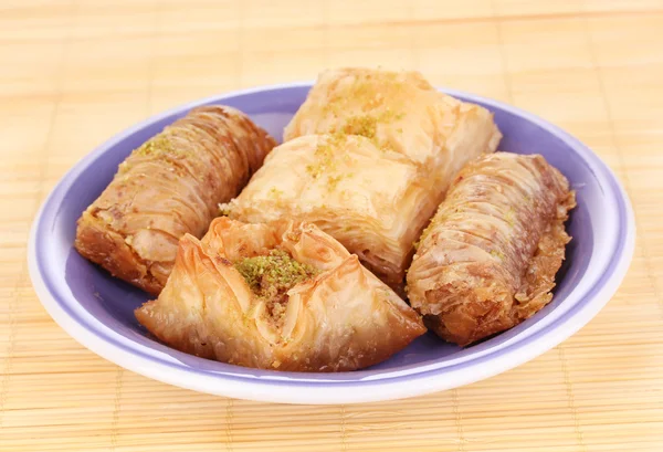 Sweet baklava on plate on bamboo mat — Stock Photo, Image