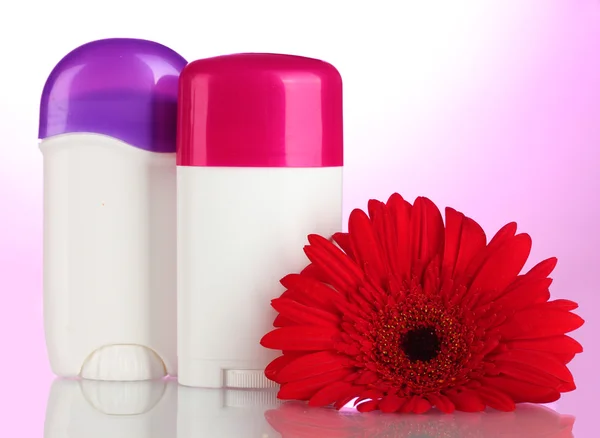 Çiçekli pembe bir arka plan üzerinde deodorantlar — Stok fotoğraf