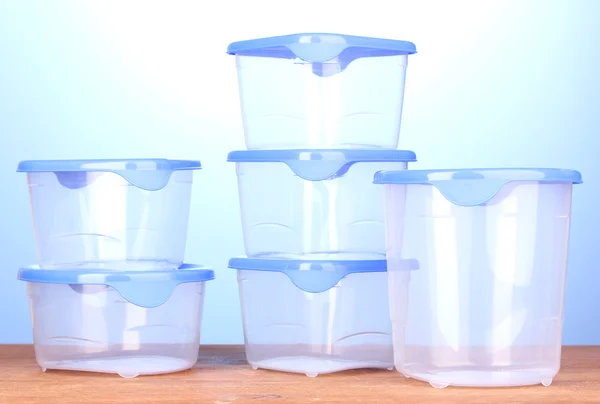 Kunststoffbehälter für Lebensmittel auf Holztisch auf blauem Hintergrund — Stockfoto