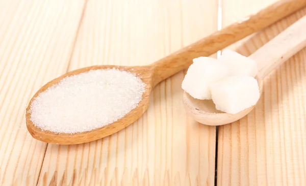 Açúcar branco em colheres no fundo de madeira — Fotografia de Stock