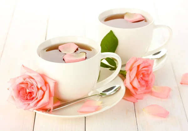 stock image Cups of tea with roses on white wooden table