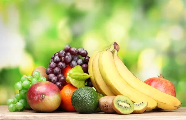 Auswahl an exotischen Früchten auf Holztisch auf grünem Hintergrund — Stockfoto