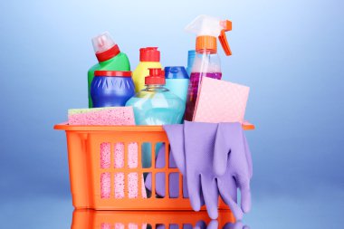 Basket with cleaning items on blue background clipart