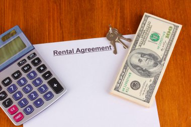 Rental agreement with dollars on wooden background close-up clipart