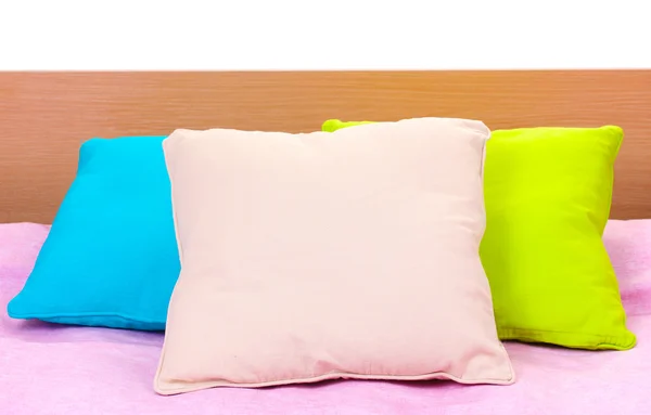Almofadas brilhantes na cama no fundo branco — Fotografia de Stock