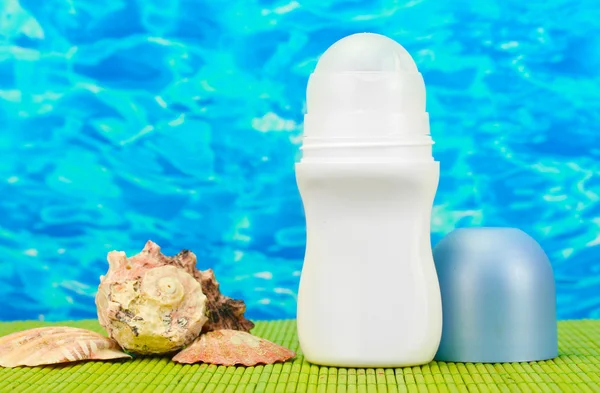 Desodorizante e conchas no fundo do mar azul — Fotografia de Stock