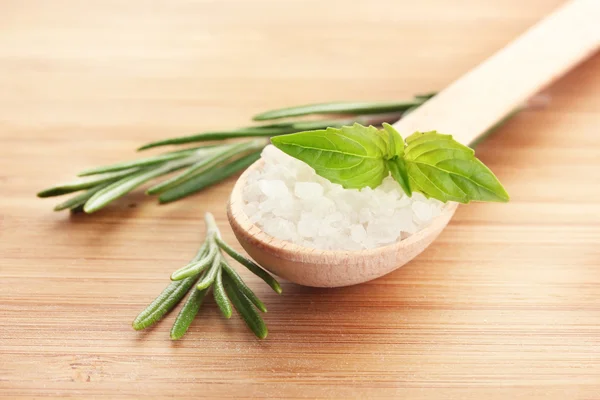 Salt in spoon with fresh rosemary and basil on wooden background — Stock Photo, Image