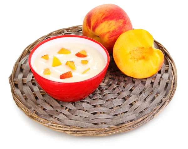 Jogurt z brzoskwini w misce na maty wiklinowe na białym tle — Zdjęcie stockowe