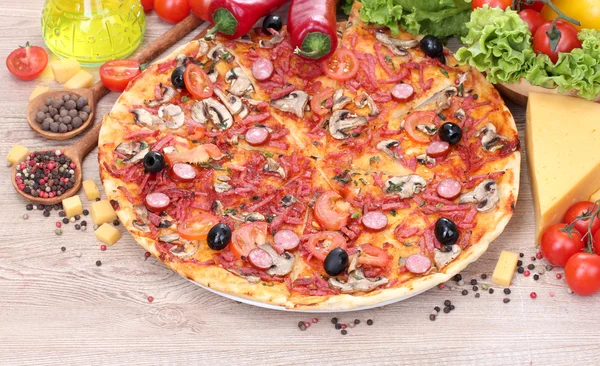 Pyszne pizzy i warzywa na drewnianym stole — Zdjęcie stockowe