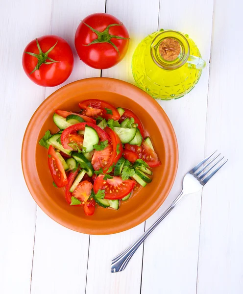 Свежий салат с помидорами и огурцами на белом деревянном фоне — стоковое фото