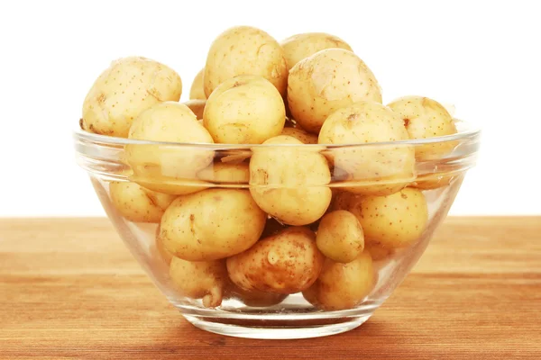 Nové brambory ve skleněné mísy na stole na bílém pozadí — Stock fotografie