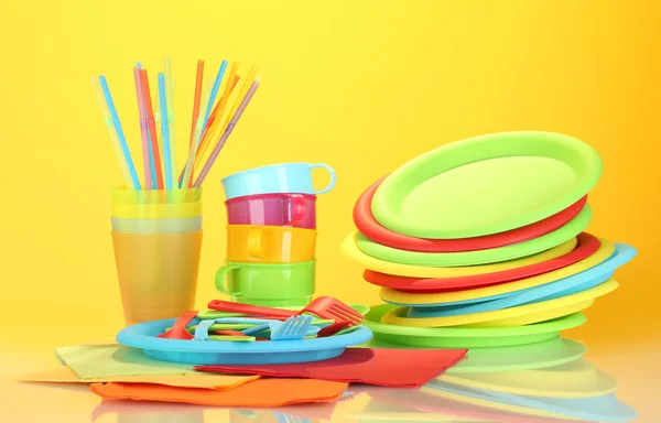 Яскравий пластиковий одноразовий посуд на барвистому фоні — стокове фото
