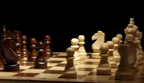 Σκακιέρα με τα κομμάτια σκακιού που απομονώνονται σε μαύρο — Φωτογραφία Αρχείου