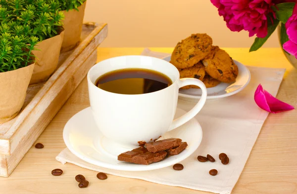 Taza de café, galletas, chocolate y flores en la mesa en la cafetería —  Fotos de Stock