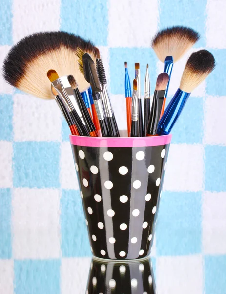 Cepillos de maquillaje en una taza de lunares negro sobre un fondo colorido —  Fotos de Stock