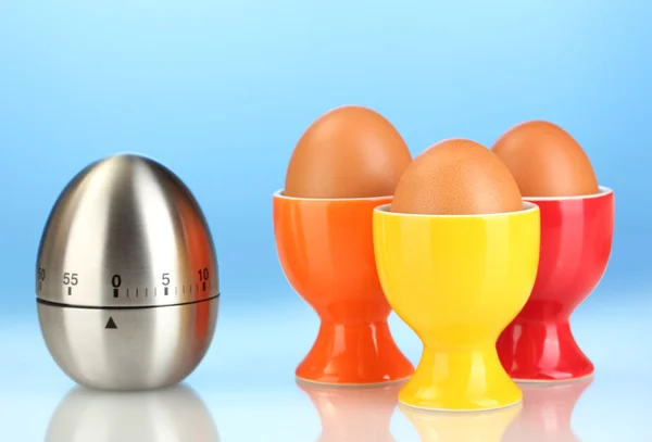 Eieruhr und Ei in Farbe stehen auf blauem Hintergrund — Stockfoto