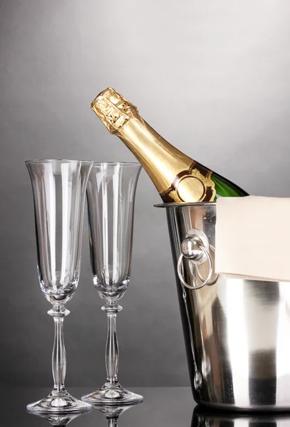 Champagne bottle in bucket with ice and glasses on grey background — Stock Photo, Image