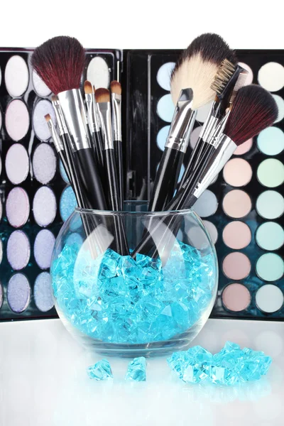 Make-up borstar i en skål med stenar på palett av skuggor bakgrund — Stockfoto