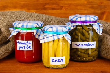 Jars with canned vegetables on wooden background close-up clipart