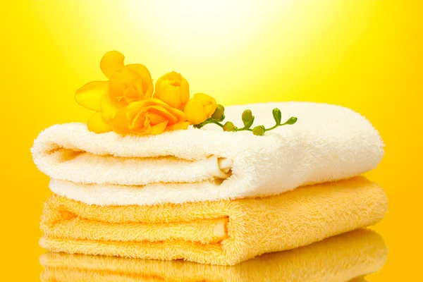 Värikkäitä pyyhkeitä ja kukkia keltaisella taustalla — kuvapankkivalokuva