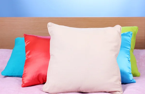明亮在蓝色背景上的床上的枕头 — 图库照片