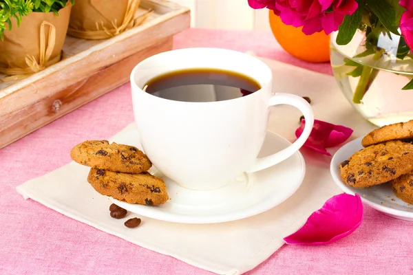Filiżankę kawy, ciasteczka, pomarańczowy i kwiaty na stole w kawiarni — Zdjęcie stockowe