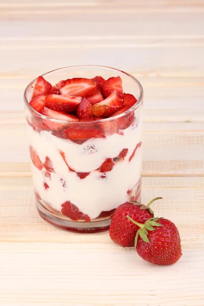 Verre de fraises mûres avec crème sur fond bois — Photo