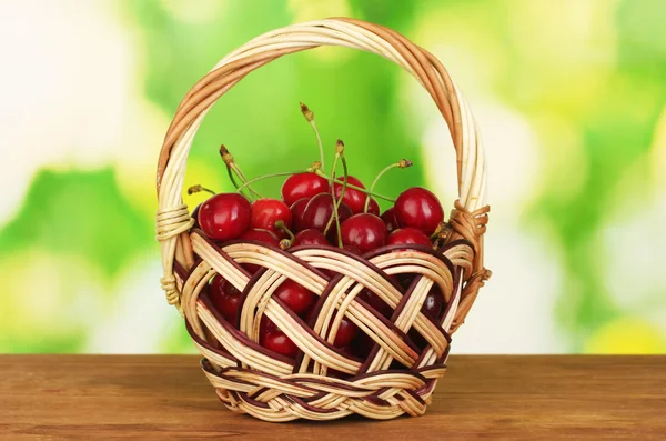 Kirsche im Korb auf Holztisch auf grünem Hintergrund — Stockfoto