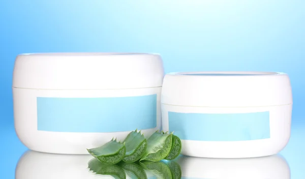 Jars of cream with aloe vera on blue background — Stock Photo, Image
