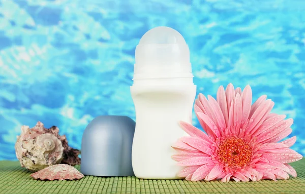 Desodorizante, flor e conchas no fundo do mar azul — Fotografia de Stock