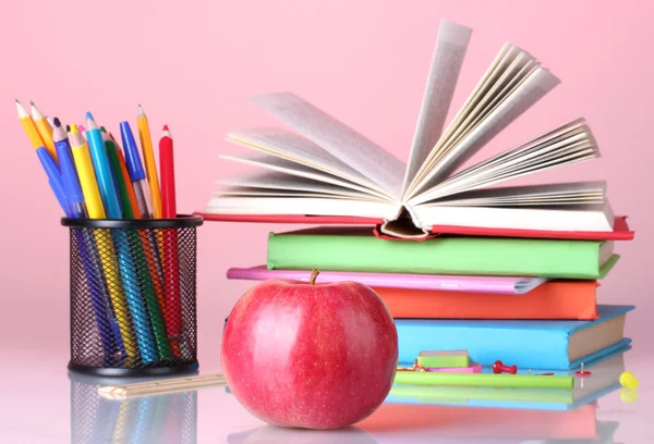 Összetételét könyvek, papíráruk és egy almát, fényes színes háttérrel — Stock Fotó