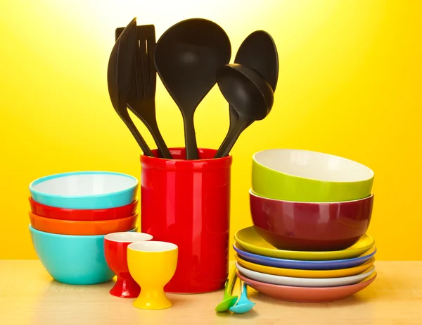 Parlak boş tabak, bardak ve Sarı zemin üzerine ahşap masa üzerinde mutfak gereçleri — Stok fotoğraf
