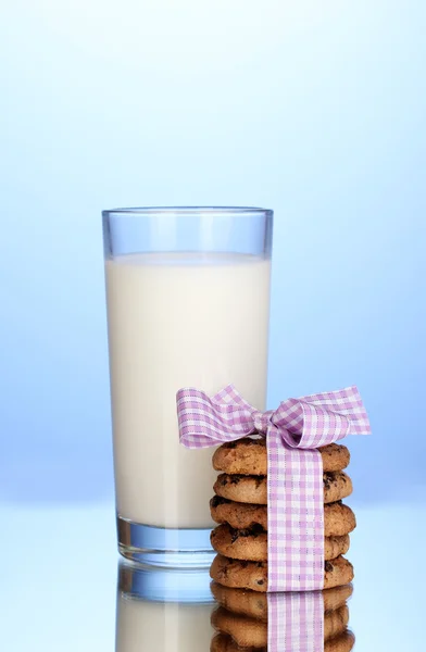 Vetro di latte e biscotti su sfondo blu — Foto Stock