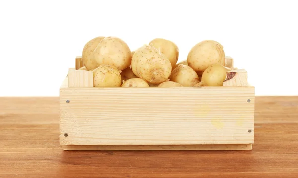 Jonge aardappelen in een houten doos op een tafel op witte achtergrond close-up — Stockfoto