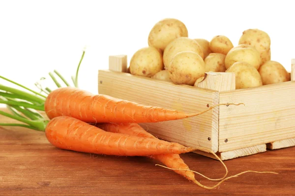 Jeunes pommes de terre dans une boîte en bois avec des carottes sur une table sur fond blanc close-up — Photo