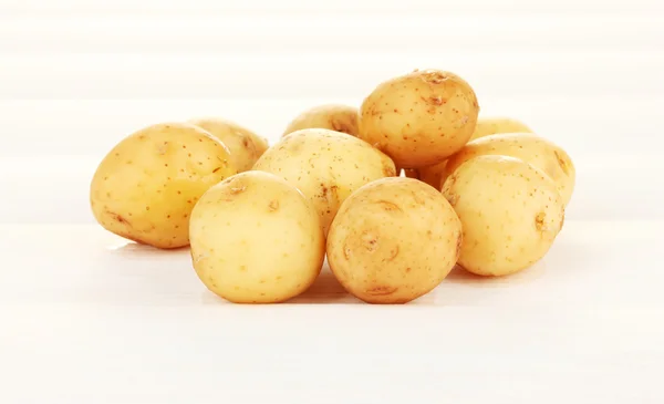 Batatas jovens em mesa de madeira branca close-up — Fotografia de Stock