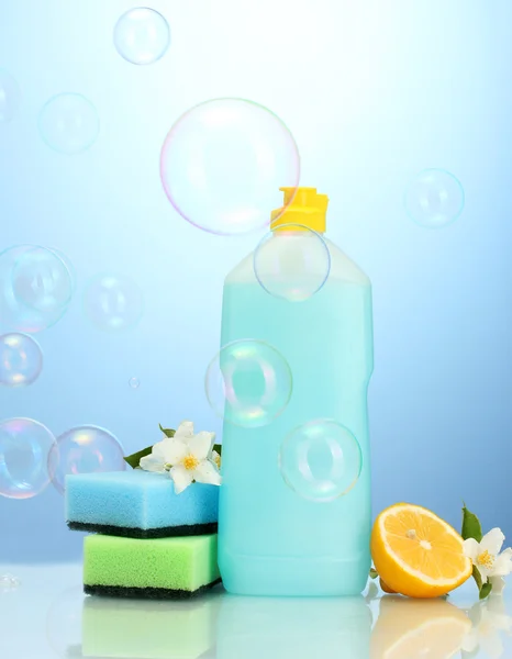 stock image Dishwashing liquid with sponges and lemon with flowers on blue background