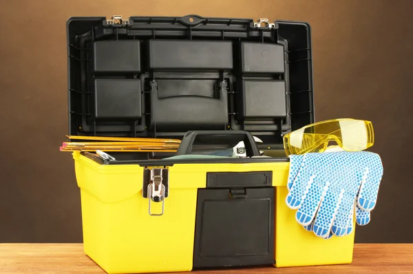 Boîte à outils ouverte jaune avec outils sur fond brun gros plan — Photo