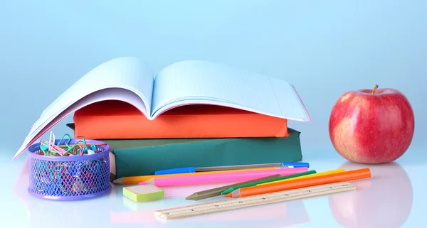 Složení knihy, papírnictví a apple na barevné pozadí — Stock fotografie