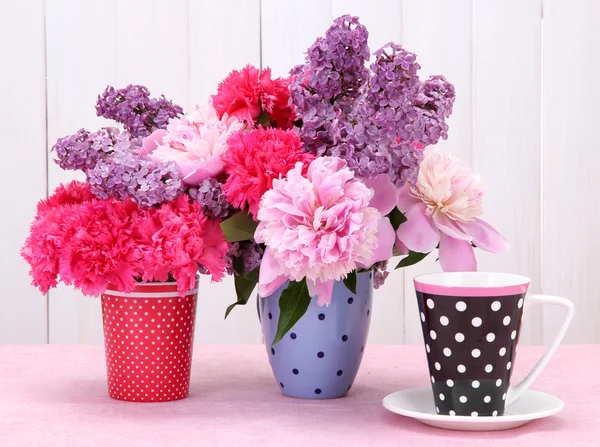 Wiosenne kwiaty i kubek na stole na białym tle drewniane — Zdjęcie stockowe