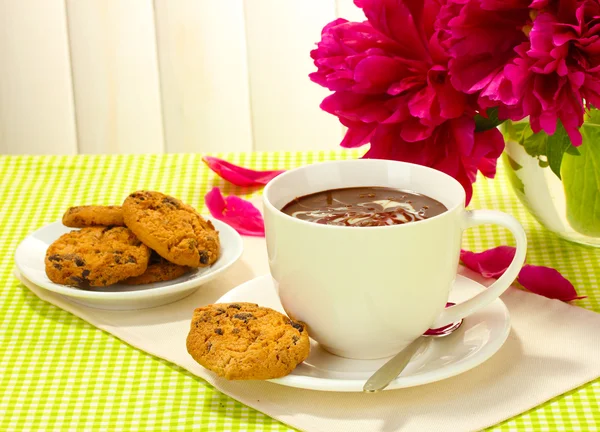Taza de chocolate caliente, galletas y flores en la mesa en la cafetería — Foto de Stock