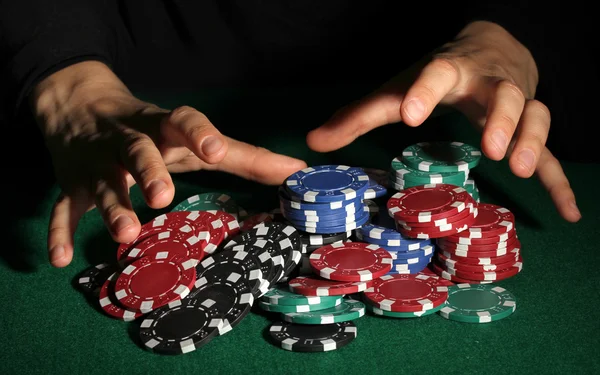 Fichas de póquer y las manos por encima de ella en la mesa verde — Foto de Stock