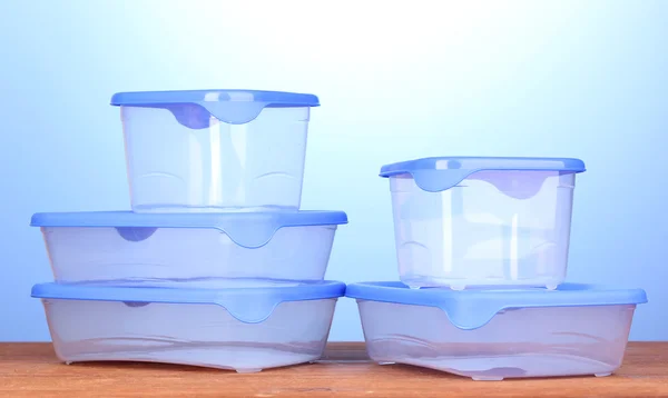 Kunststoffbehälter für Lebensmittel auf Holztisch auf blauem Hintergrund — Stockfoto