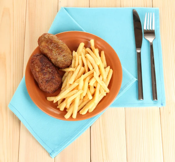 Patate fritte con hamburger sul piatto su fondo di legno primo piano — Foto Stock