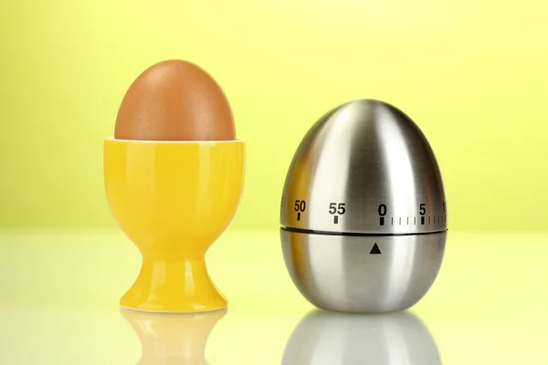 Яйцо таймер и яйцо в оранжевый стоять на зеленом фоне — стоковое фото