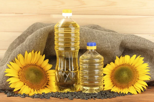 Sonnenblumenöl und Sonnenblumen auf Holz Hintergrund — Stockfoto