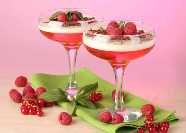 Gelée de fruits avec des baies dans des verres sur table en bois sur fond rose — Photo