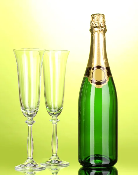 Flasche Champagner und Becher auf grünem Hintergrund — Stockfoto