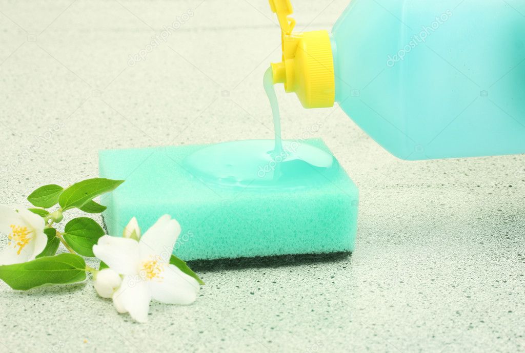 Bright sponge and flower with dish washing liquid on marble background
