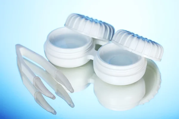 Kontaktlinser i behållare och pincett på blå bakgrund — Stockfoto